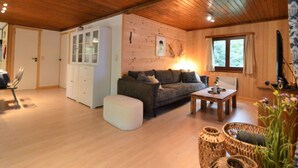 A cozy cabin interior with wooden walls, a sofa, a dining table, and a cabinet. - Cozy Chalet With Barbecue (Viroinval)