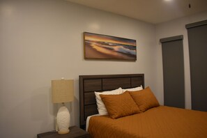 Ein Schlafzimmer mit einem Bett, einem Nachttisch mit Lampe, einem Bild an der Wand und einem Kleiderschrank.
