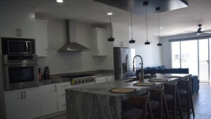 Une cuisine moderne dotée d’un îlot central, de tabourets de bar et d’une grande fenêtre.
