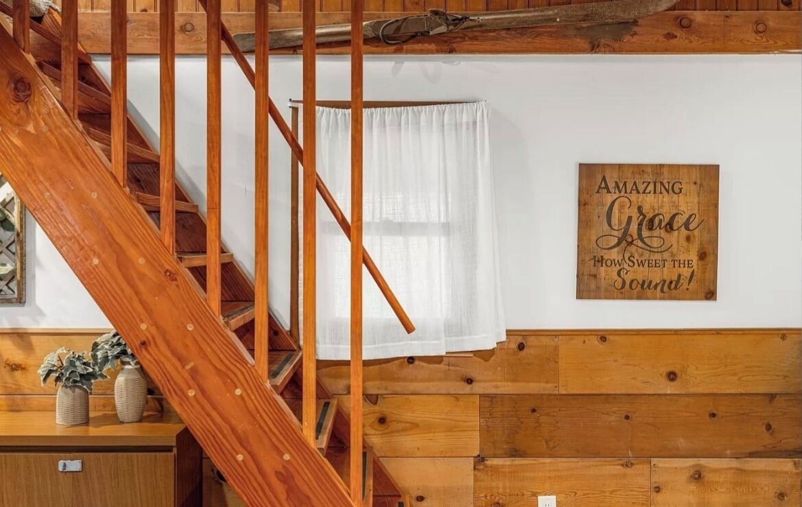 Eine Holztreppe mit weißem Vorhang und einem Schild mit der Aufschrift 'Amazing Grace How Sweet the Sound!'