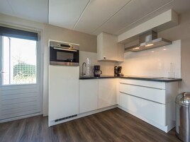 Eine moderne Küche mit weißen Schränken, einem eingebauten Backofen und einer Edelstahl-Dunstesse.