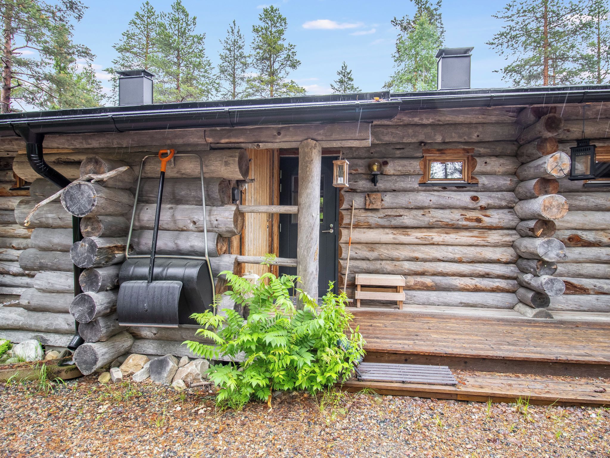 A log cabin with a wooden door, a black barrel, and a small window.