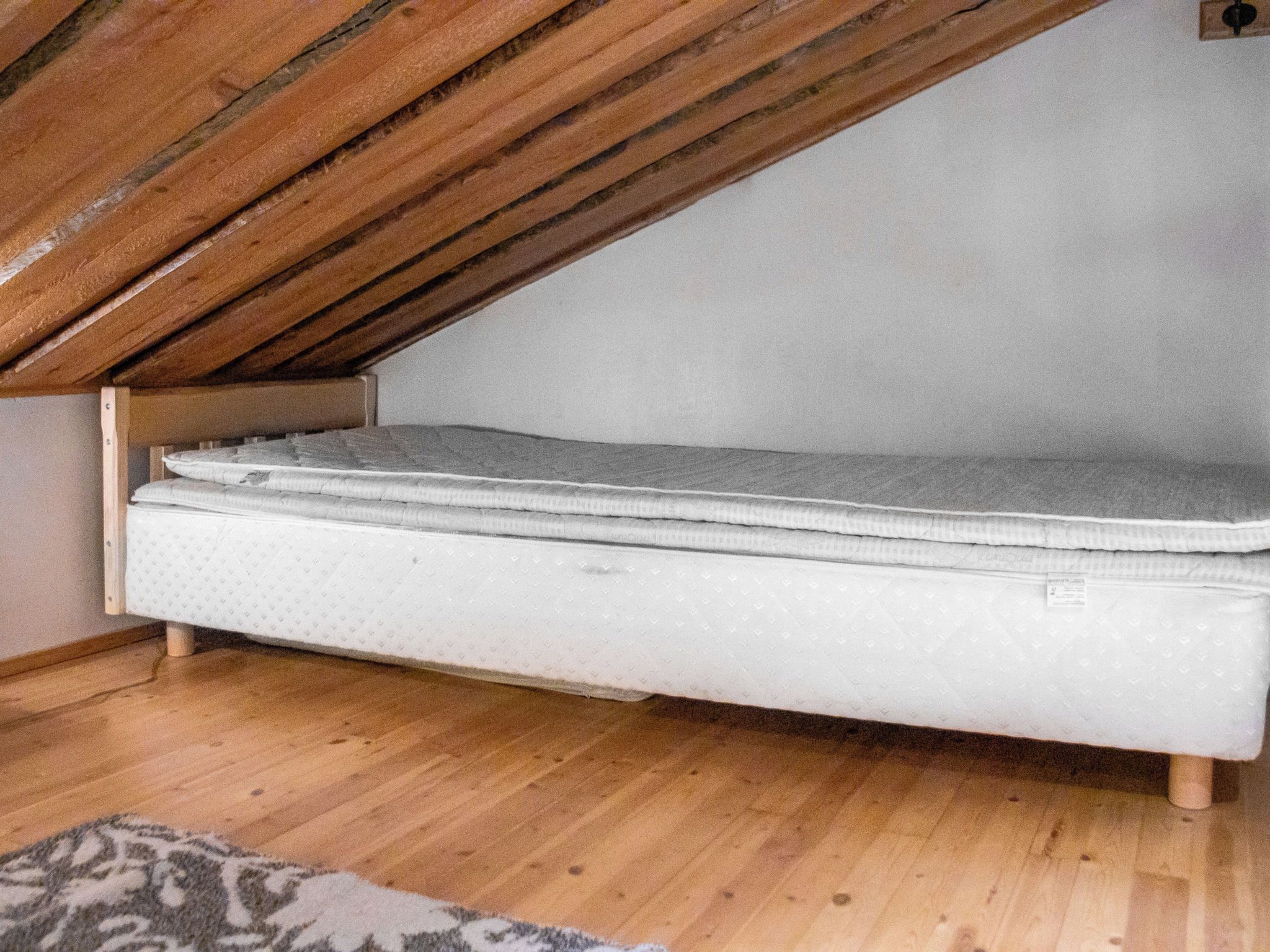 Un dormitorio estilo loft con colchón y vigas de madera.