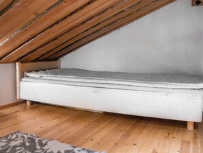 Een slaapkamer in een loft met een matras en houten balken.