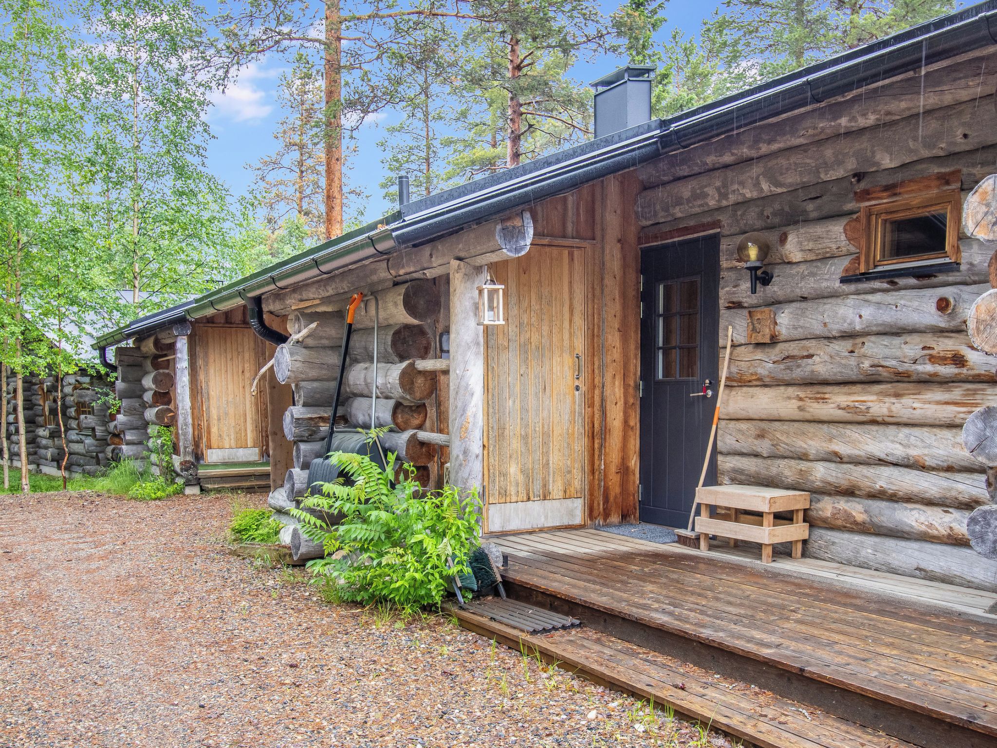 A rustic log cabin with a wooden deck and a door.
