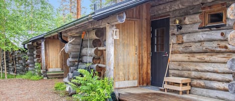 A rustic log cabin with a wooden deck and a door.