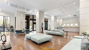 A spacious hotel lobby with a reception desk, seating areas, and a large window offering a view of the outdoors. - Modern Grove Suite | Walk to Parks & Bayfront (Miami)
