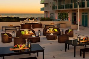 Eine Dachterrasse mit Außenmöbeln, einer Bar und Blick auf das Meer.