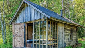 A rustic cabin with a large glass door and a wooden porch.