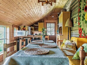 Interior acollidor d'una cabana amb menjador, cuina i una finestra gran.