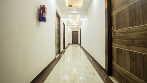 A corridor with a polished marble floor, wooden doors, and recessed ceiling lighting. - Roomsity Pride (New Delhi)