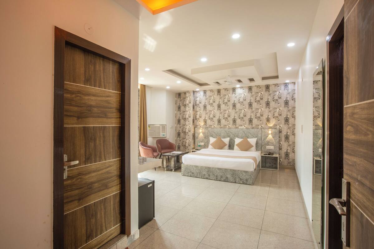 Ein modernes Hotelzimmer mit einem großen Bett, einem Schreibtisch, einem Sessel und einem kleinen Tisch.