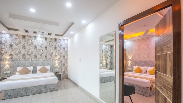A modern hotel room with a large bed, a sitting area, and a bathroom with a large mirror. - Roomsity Pride (New Delhi)