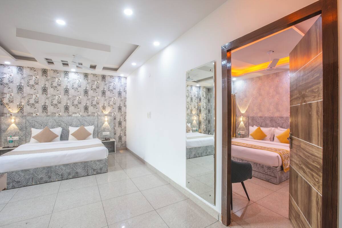 Ein modernes Hotelzimmer mit einem großen Bett, einer Sitzecke und einem Badezimmer mit einem großen Spiegel.