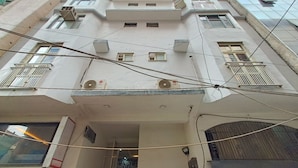 A multi-story building with balconies, air conditioning units, and visible electrical wiring. - Roomsity Pride (New Delhi)