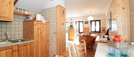 Eine Küche mit Holzschränken, einer gefliesten Spritzschutzwand und einem Essbereich mit Holztischen und einem Tisch.