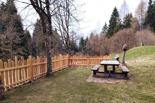 Un área de picnic con un cerco de madera, una mesa y un sendero de piedra.