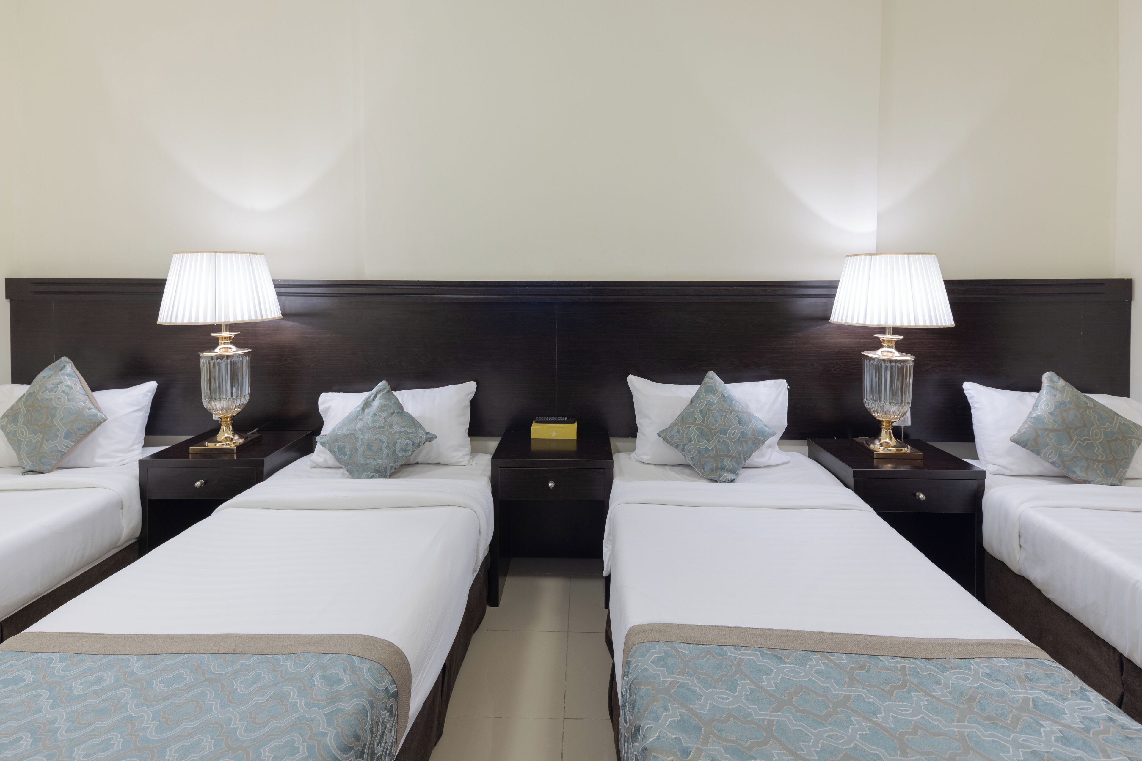 Une chambre d’hôtel avec deux lits simples, chacun étant équipé d’une table de chevet, d’une lampe et d’une petite table.