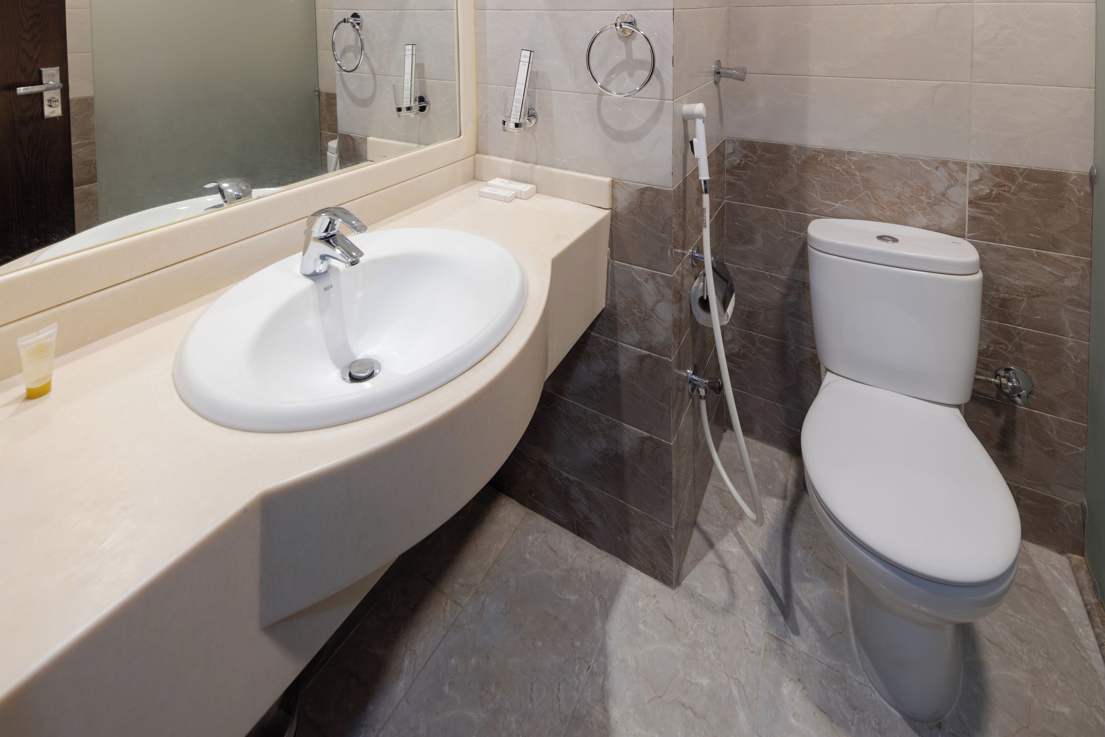 A modern bathroom with a white sink, a mirror, a toilet, and a shower.
