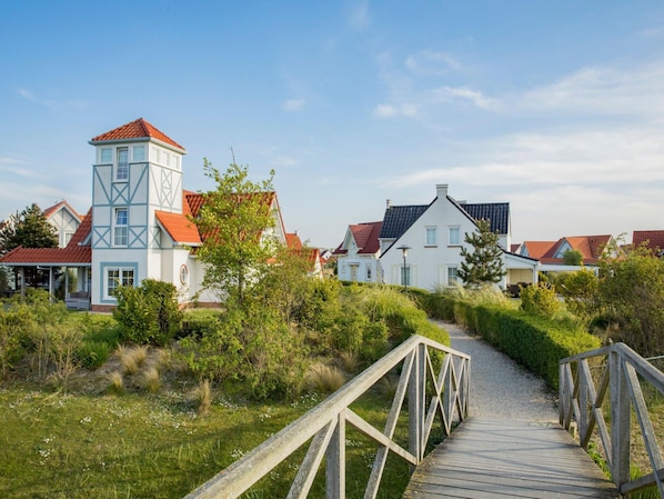 A pathway leading to a row of houses with a prominent tower-like structure.