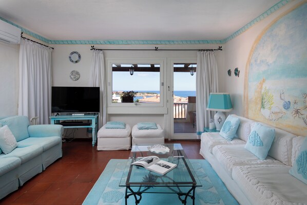 A living room with a TV, two sofas, a coffee table, and a view of the sea. - Cerbiatta al Molo Apartments by Wonderful Italy (Arzachena)