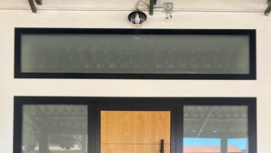 Une entrée moderne avec une grande porte en verre, une porte à panneaux en bois et une poignée en métal.