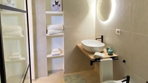 Une salle de bain moderne dotée d’une douche à parois de verre, d’un lavabo encastré, d’un bidet et d’un porte-serviettes.