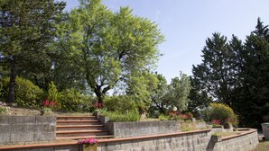 Un mur de soutènement en pierre, agrémenté d’un escalier menant à un espace jardin aménagé avec différentes plantes et fleurs.
