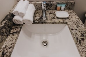 A bathroom sink with a granite countertop, a faucet, and a soap dish.