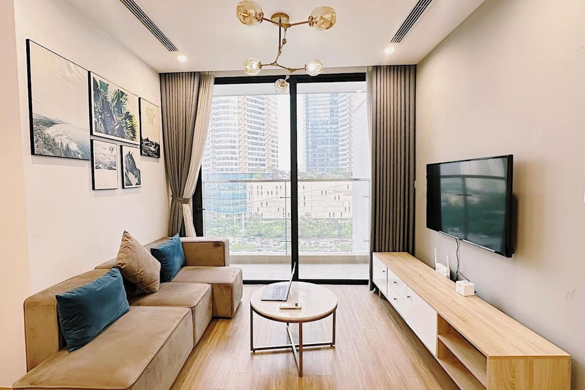 A modern living room with a sofa, coffee table, TV, and artwork on the wall.