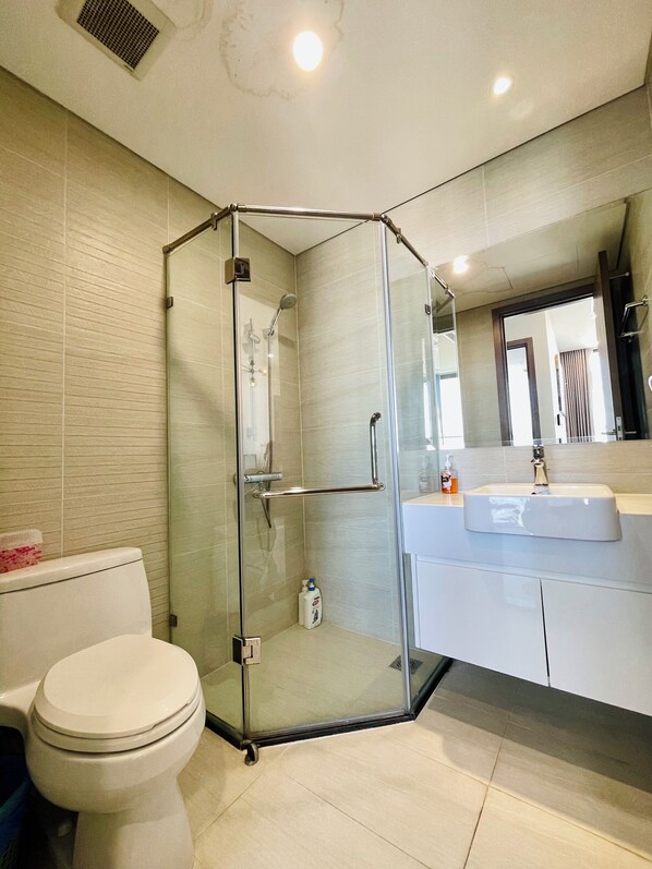 A modern bathroom with a glass-enclosed shower, a toilet, and a vanity with a sink. - HMH - Vinhomes Skylake - Dream apartment (Hanoi)