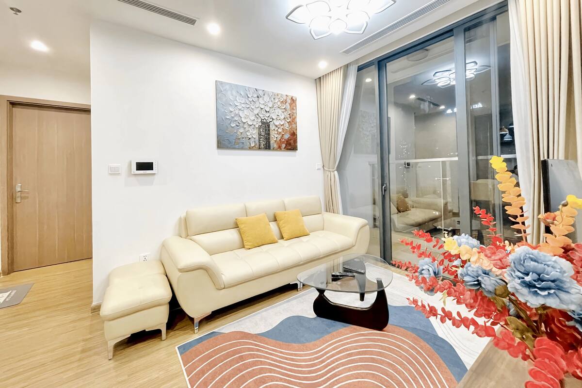 A modern living room with a sofa, a glass coffee table, and a decorative rug.