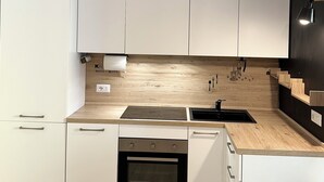 A modern kitchen with white cabinets, a black stove, and a wooden countertop.