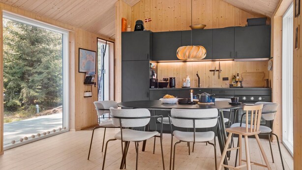 A modern kitchen with a central island, grey upholstered chairs, and wooden flooring. - 3 bedroom amazing home in Stege (Stege)