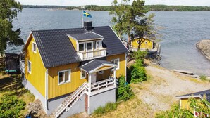 A yellow house with a balcony, a small boat, and a flag. - 4 bedroom amazing home in Sorunda (Sorunda)