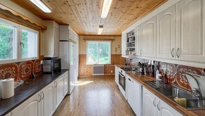 A kitchen with wooden ceiling, white cabinets, and a view of greenery outside. - 4 bedroom amazing home in Sorunda (Sorunda)
