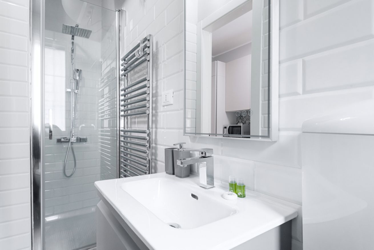 Un baño moderno con cabina de ducha de vidrio, un lavabo blanco y un perchero para toallas.
