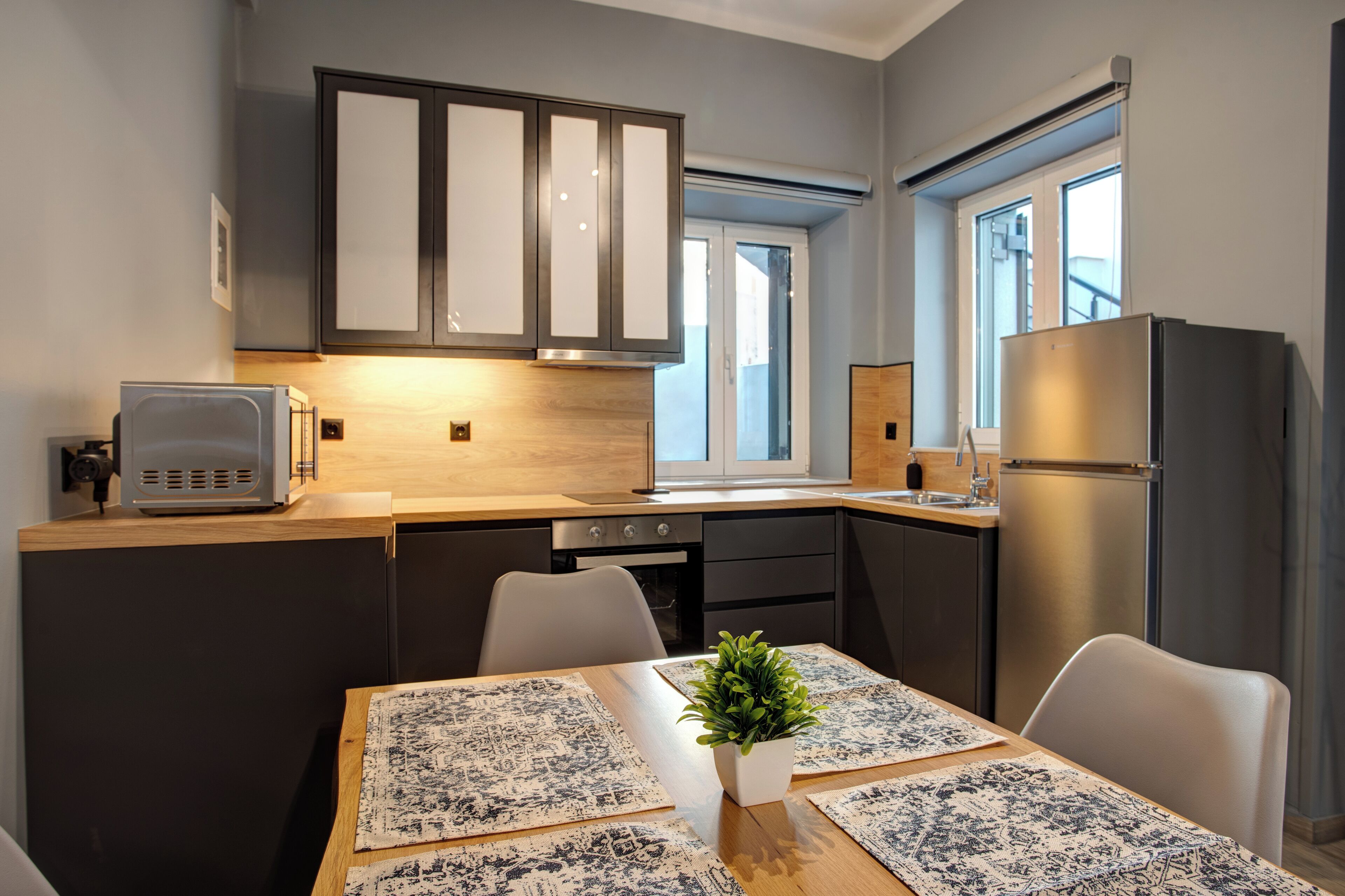A modern kitchen with dark cabinets, a built-in microwave, and a stainless steel refrigerator.