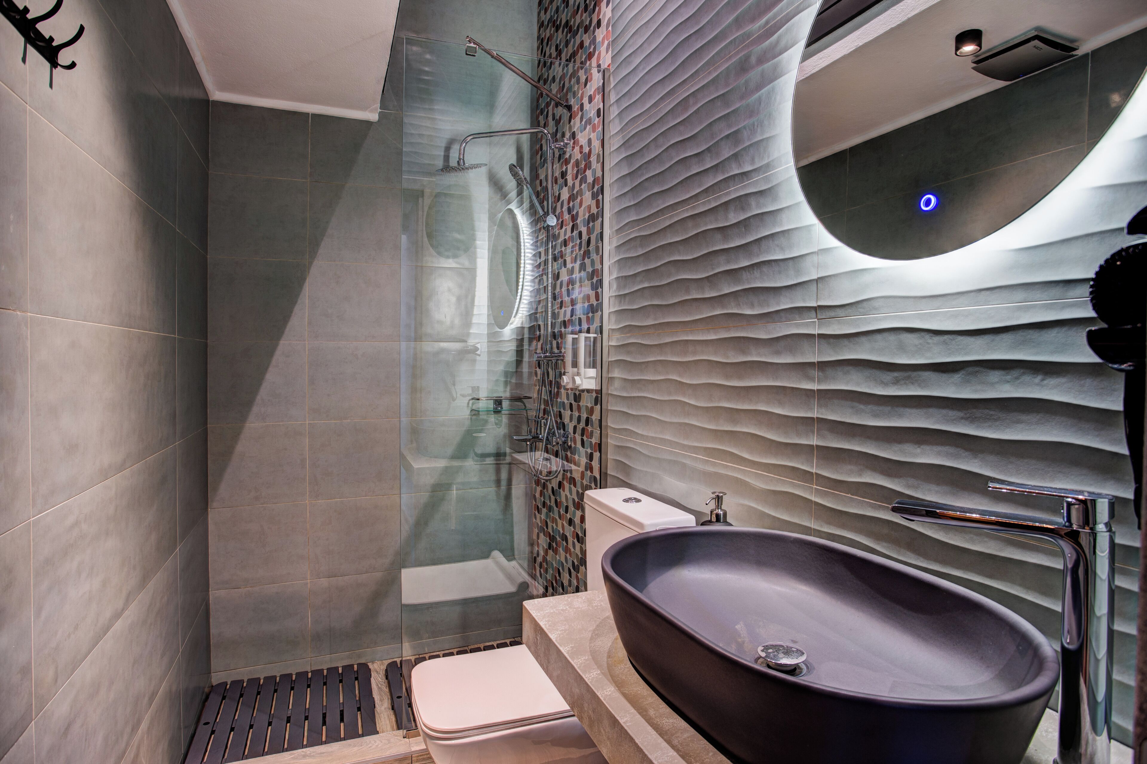 A modern bathroom with a glass-enclosed shower, a freestanding bathtub, and a wall-mounted sink.
