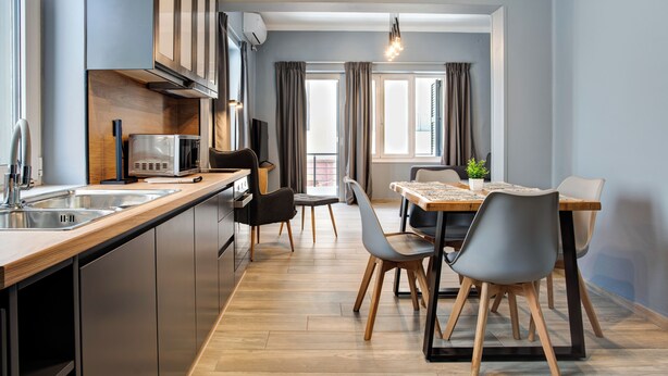 A modern kitchen with stainless steel appliances, a wooden countertop, and a dining area with a table and chairs. - Agora Apartments (Lesvos)
