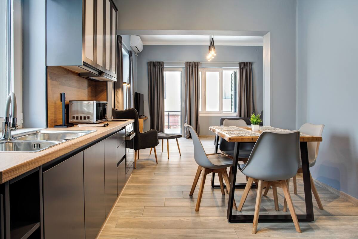 Une cuisine moderne dotée d’appareils électroménagers en acier inoxydable, d’un plan de travail en bois et d’un coin repas avec une table et des chaises.