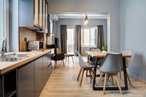 A modern kitchen with stainless steel appliances, a wooden countertop, and a dining area with a table and chairs. - Agora Apartments (Lesvos)