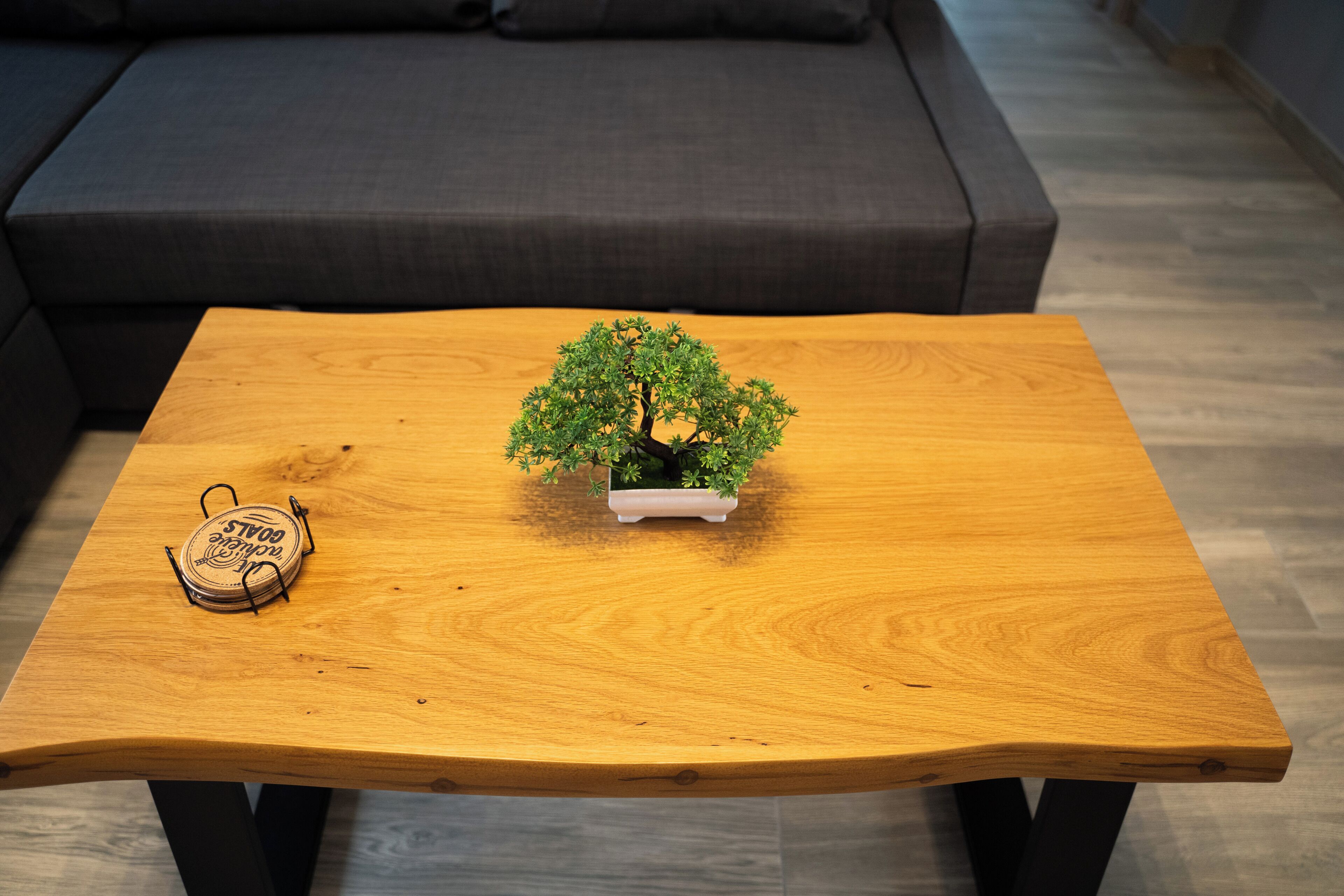 Uma mesa de centro de madeira com uma árvore bonsai e um apoio decorativo para bebidas.
