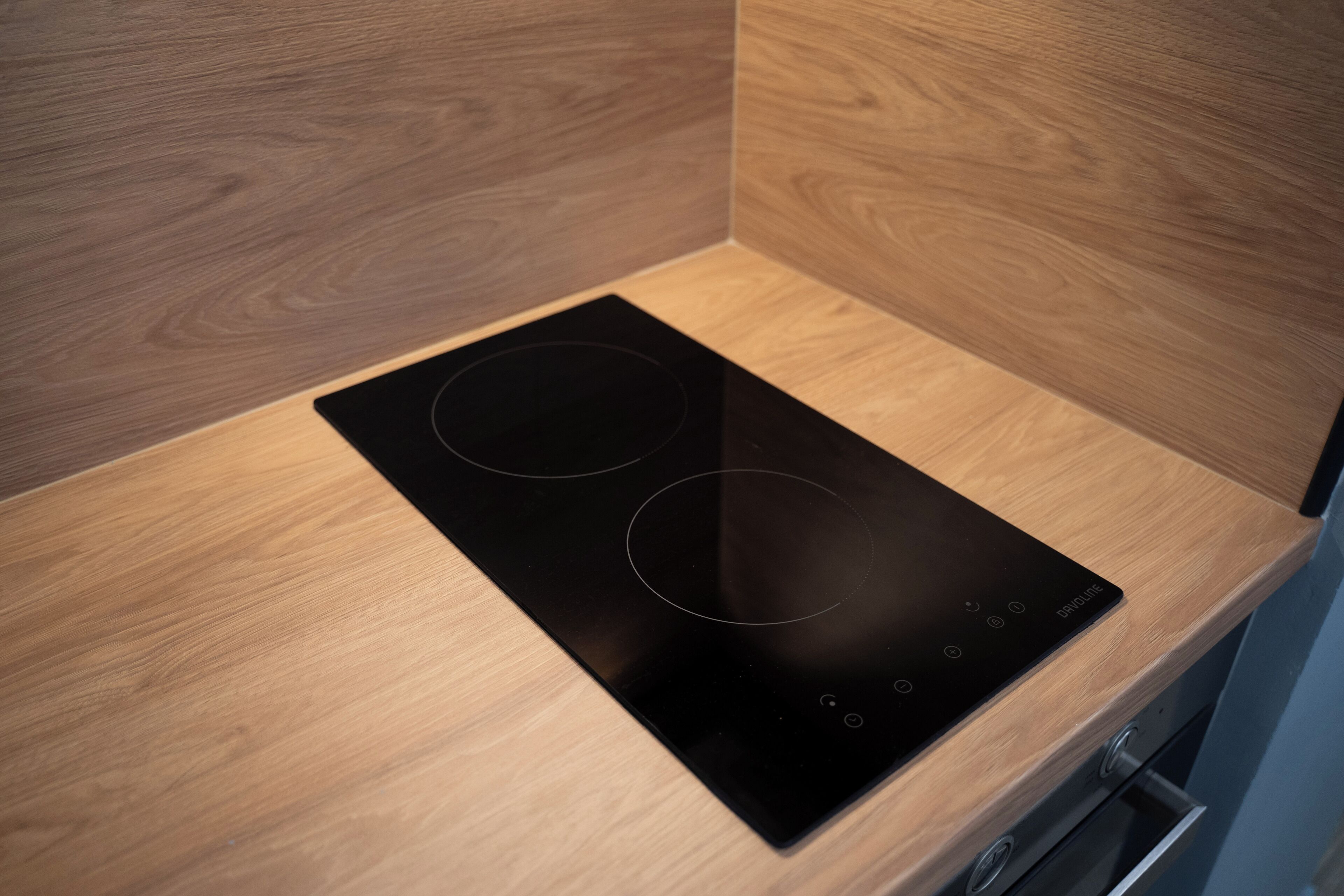 Une plaque de cuisson à induction noire, posée sur un plan de travail en bois.