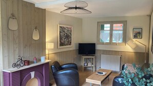 A living room with a fireplace, leather sofas, a TV, and a window with a view. - House with garden in the heart of the village of Gerde. Pets allowed. (Gerde)