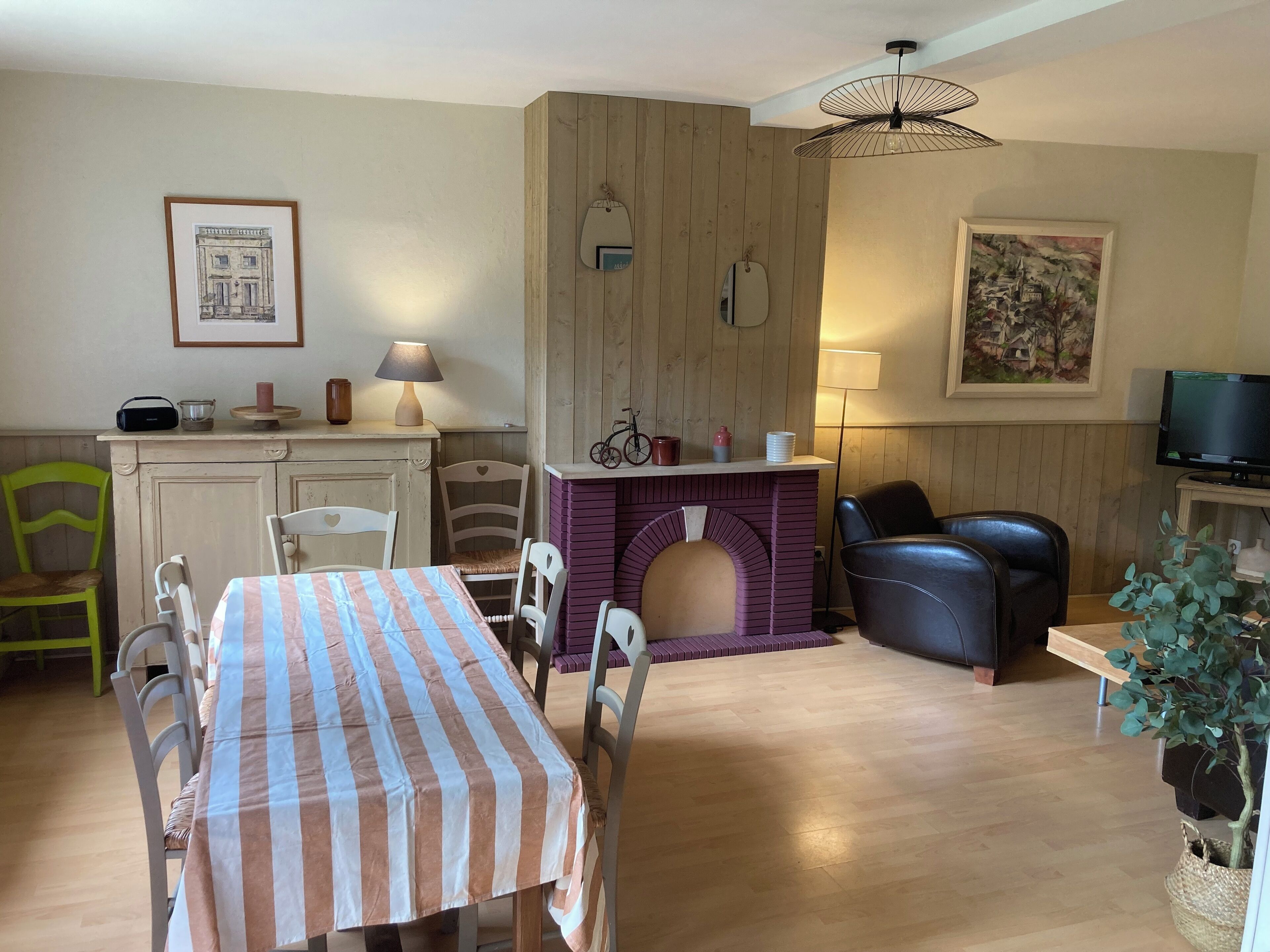 Ein gemütliches Wohnzimmer mit Esstisch, Stühlen, Kamin, Fernseher und Lampe.