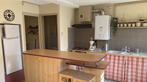 A kitchen with a wooden bar counter, a refrigerator, a stove, and a sink. - House with garden in the heart of the village of Gerde. Pets allowed. (Gerde)