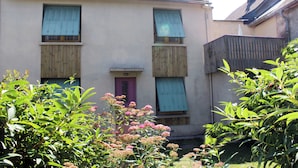 A two-story house with a pink door and shutters, surrounded by greenery. - House with garden in the heart of the village of Gerde. Pets allowed. (Gerde)