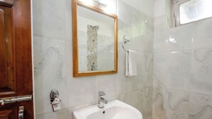 A bathroom with a white sink, a wooden door, and a mirror with a decorative frame. - Vivaan Stay Holiday Home international (Manali)