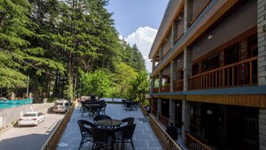 A hotel with outdoor seating, a view of the road, and trees. - Vivaan Stay Holiday Home international (Manali)